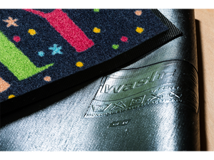 Rückenansicht der dunkelblauen Fußmatte mit buntem Schriftzug "Happy Family" und Regenbogen